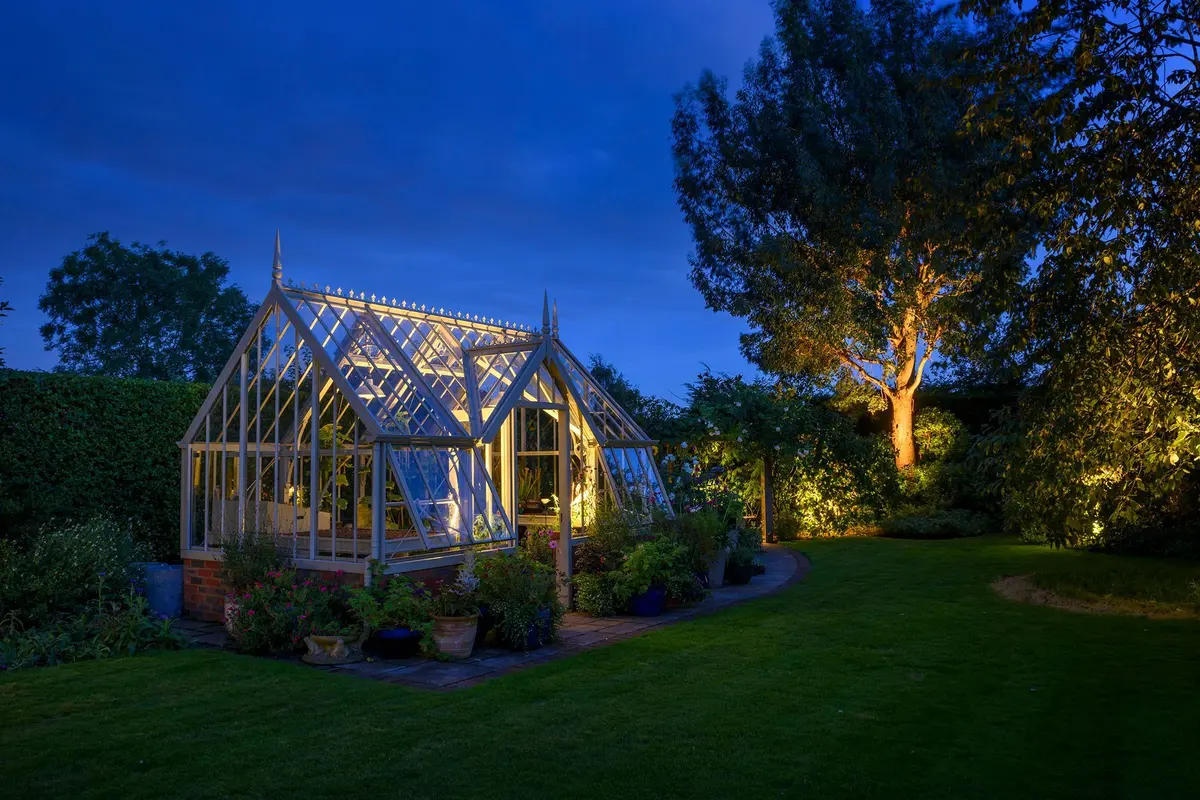 Ornate Victorian greenhouse illuminated from within at blue hour